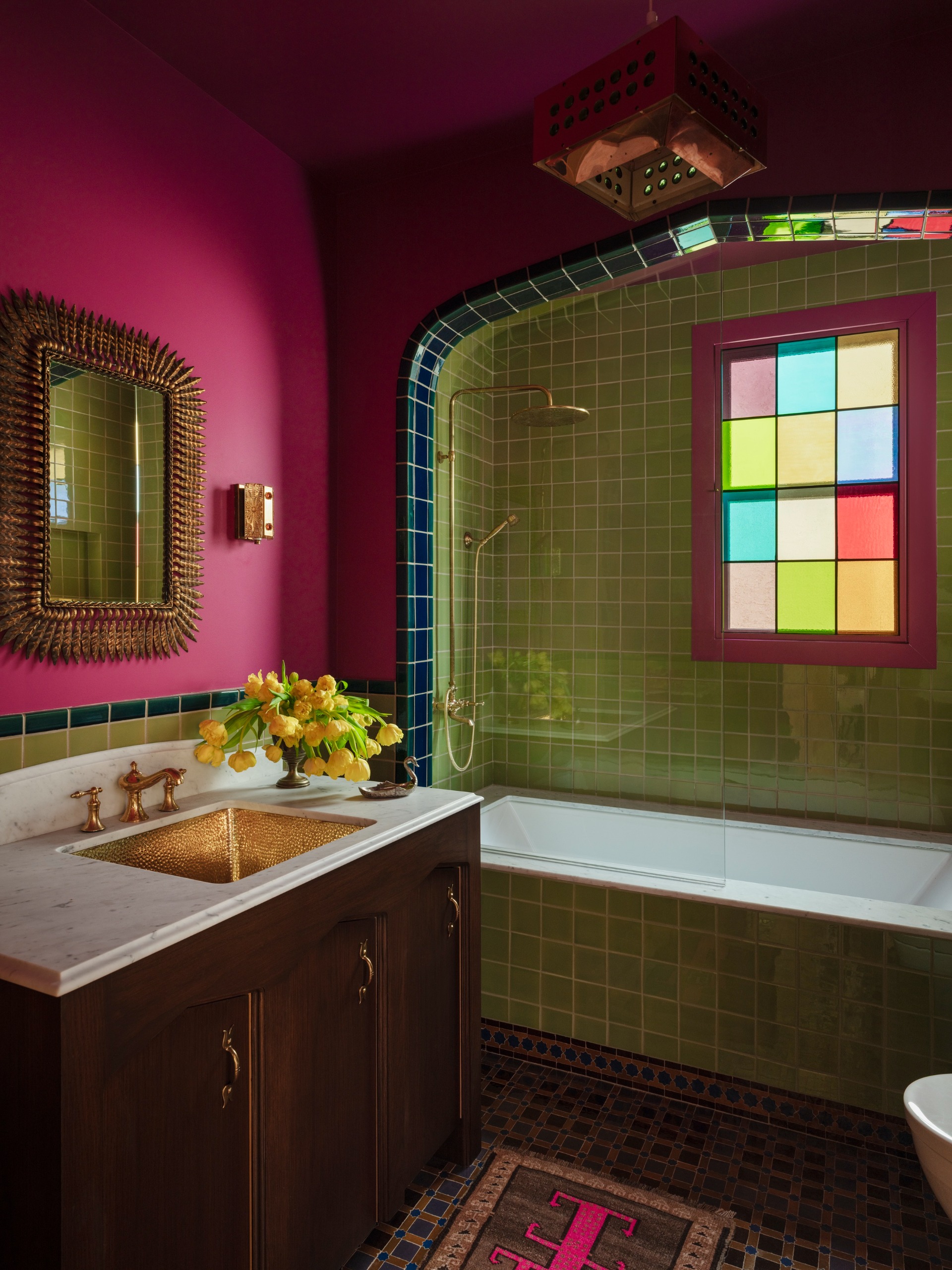 a pink and green bathroom with a dark border tile