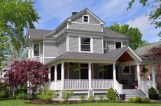 A large, well-kept suburban home with a large garden and front porch.
