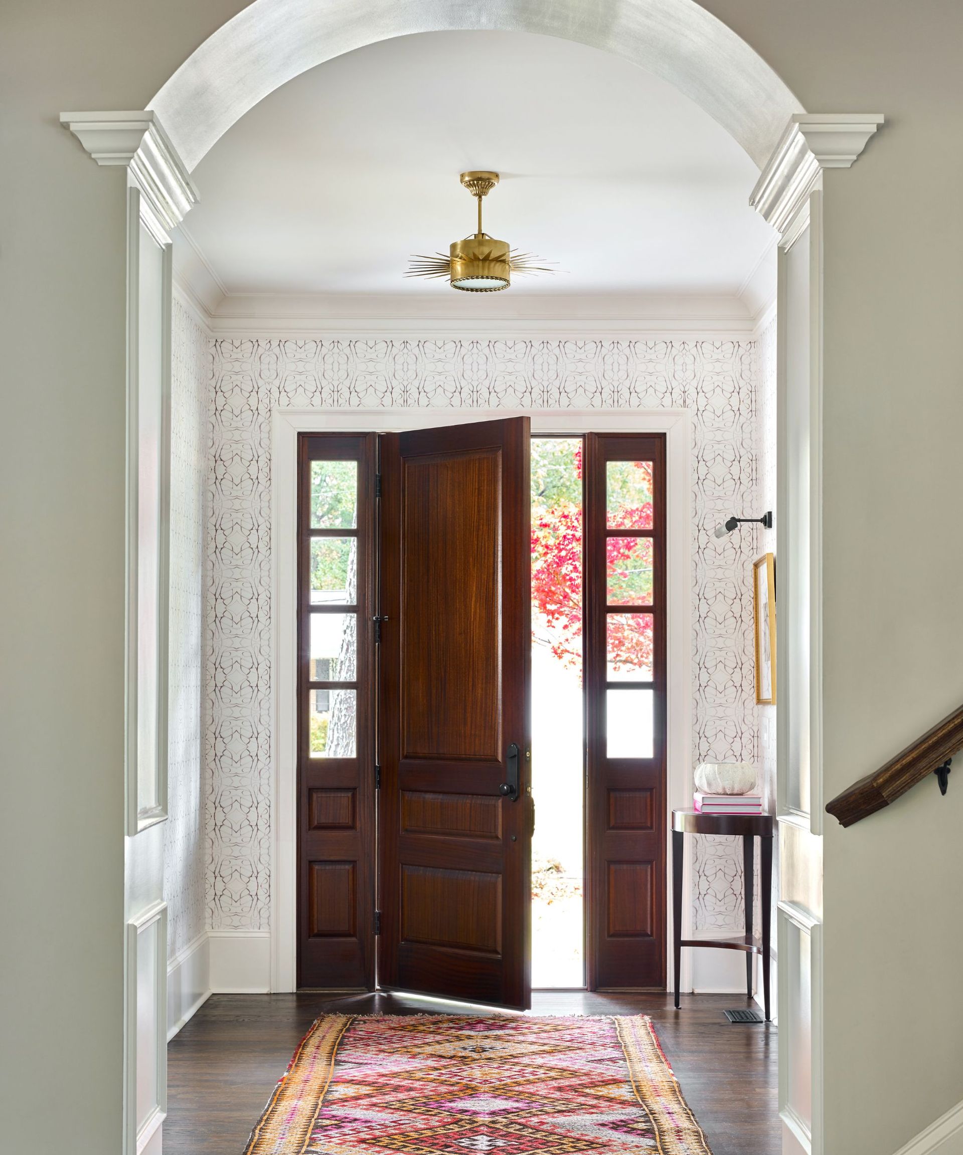 hallway with patterned wall covering and arched molding