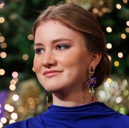 Princess Elisabeth wearing a blue gown and long statement earrings in front of a Christmas tree