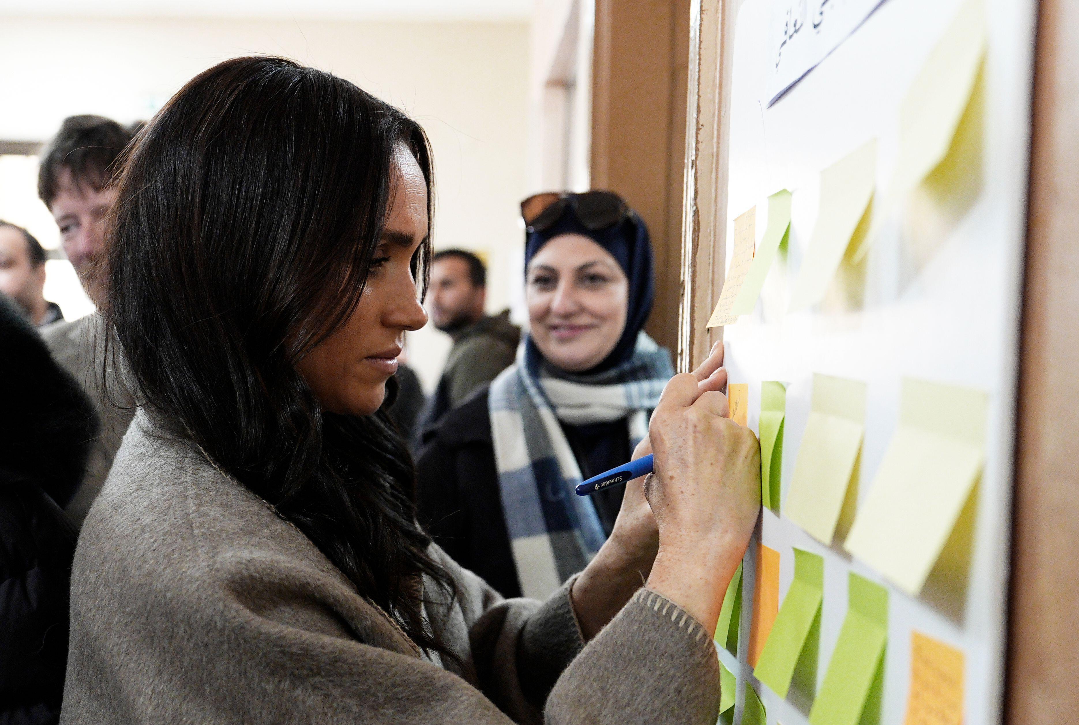 Meghan Markle writing a message on a sticky note