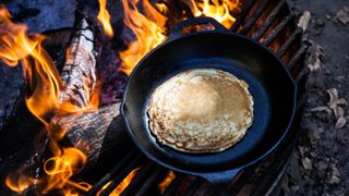 Pancakes in a skillet over a campfire