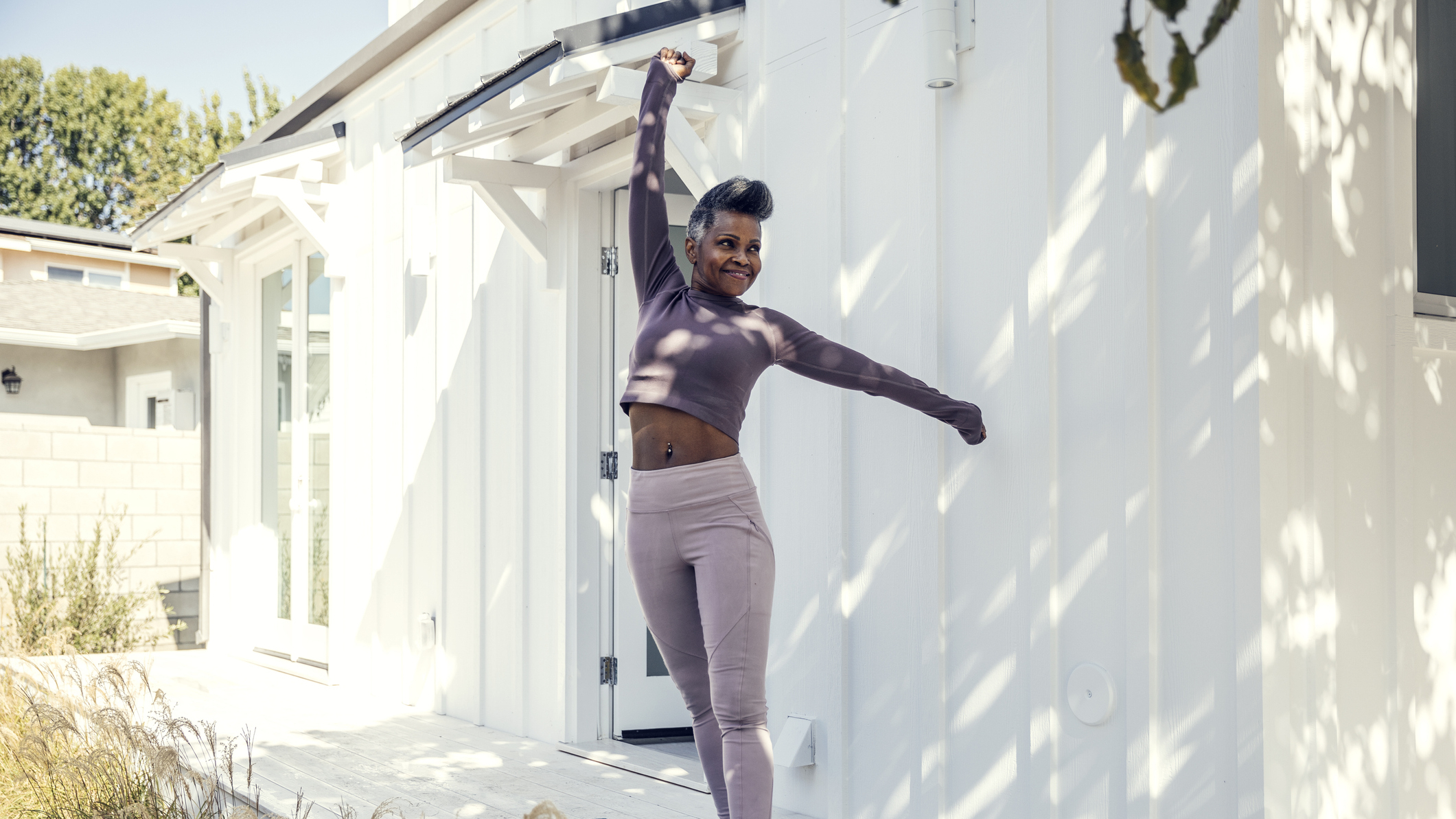 Woman stretches outside a house