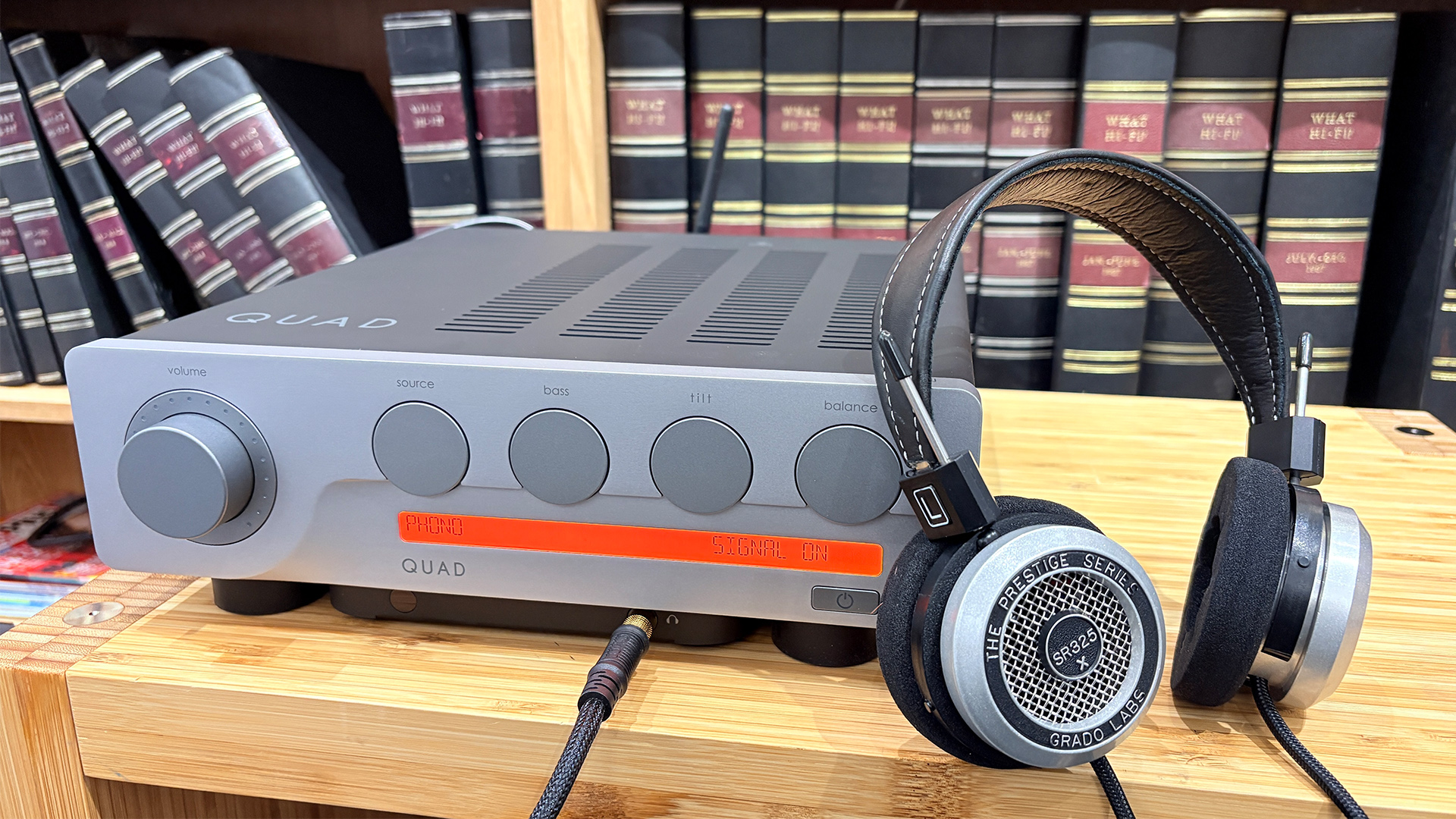 Quad 3 integrated amplifier on wooden AV rack in front of bookcase with Grado headphones
