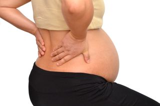 A pregnant woman rubs her lower back.