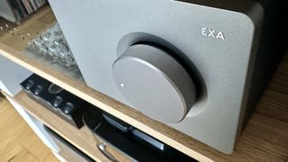 Close-up of the dial knob of a Cambridge Audio EXA100 amplifier, on a wooden shelf