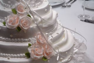 A wedding cake with roses and ribbons.