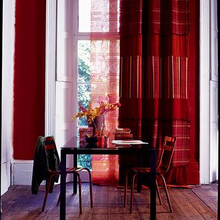 dining area with red curtains and white wall and wooden floor and table and chairs