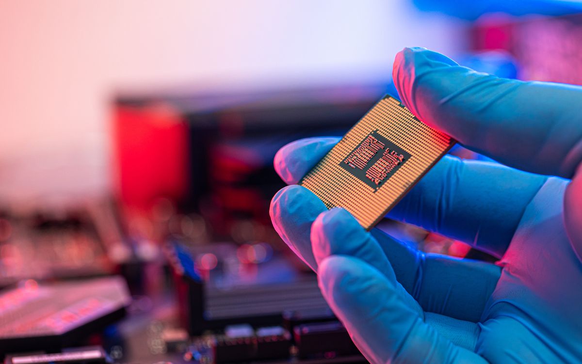 A person wearing a blue glove holding a CPU