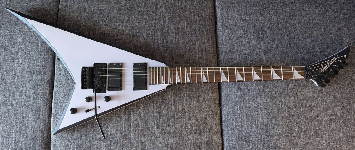 A Jackson X Series Rhoads RRX24 lying on a grey sofa