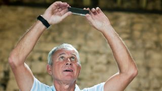 Man looks up at phone held above head for reception