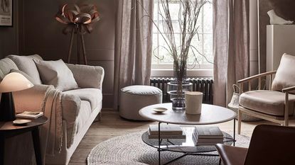 A cream and brown living room with statement textured floor lamp, upholstered sofa, jute round rug and wooden flooring