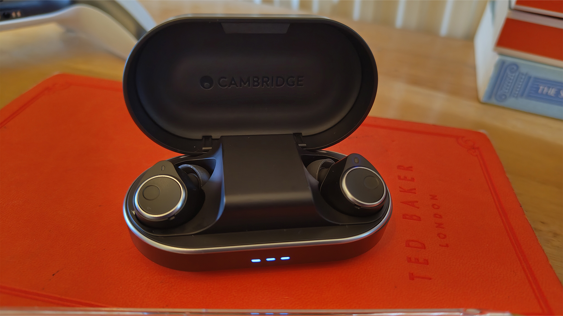 Cambridge Audio Melomania M100 wireless earbuds in case on red surface