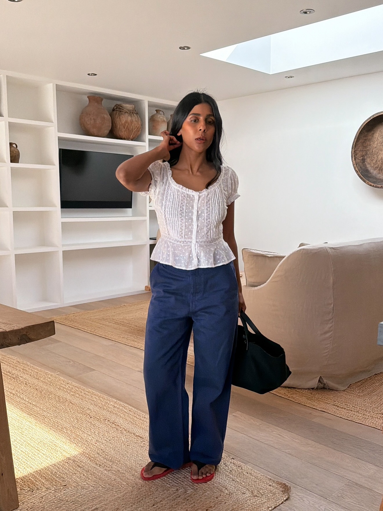 Monikh wears a white blouse, navy cargo trousers, and flip flops