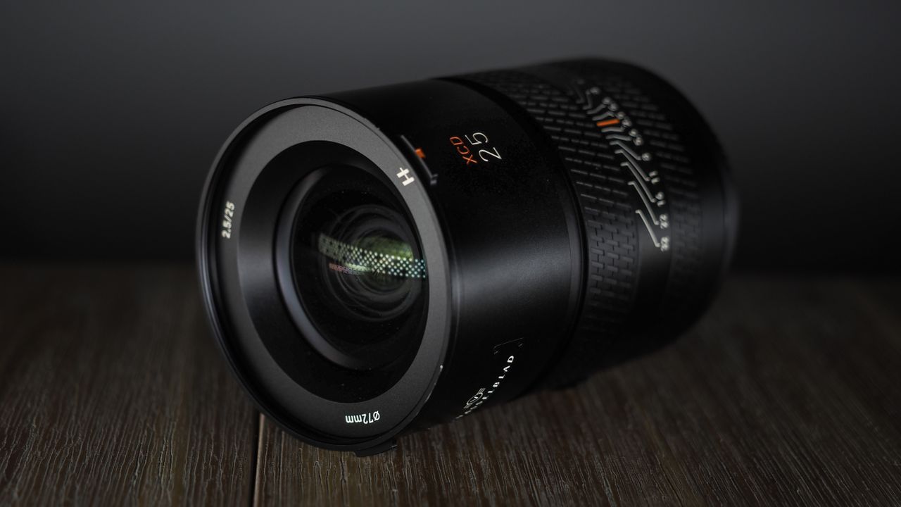 Hasselblad XCD 25V lens, on a wooden table, shot with dramatic light against a dark background