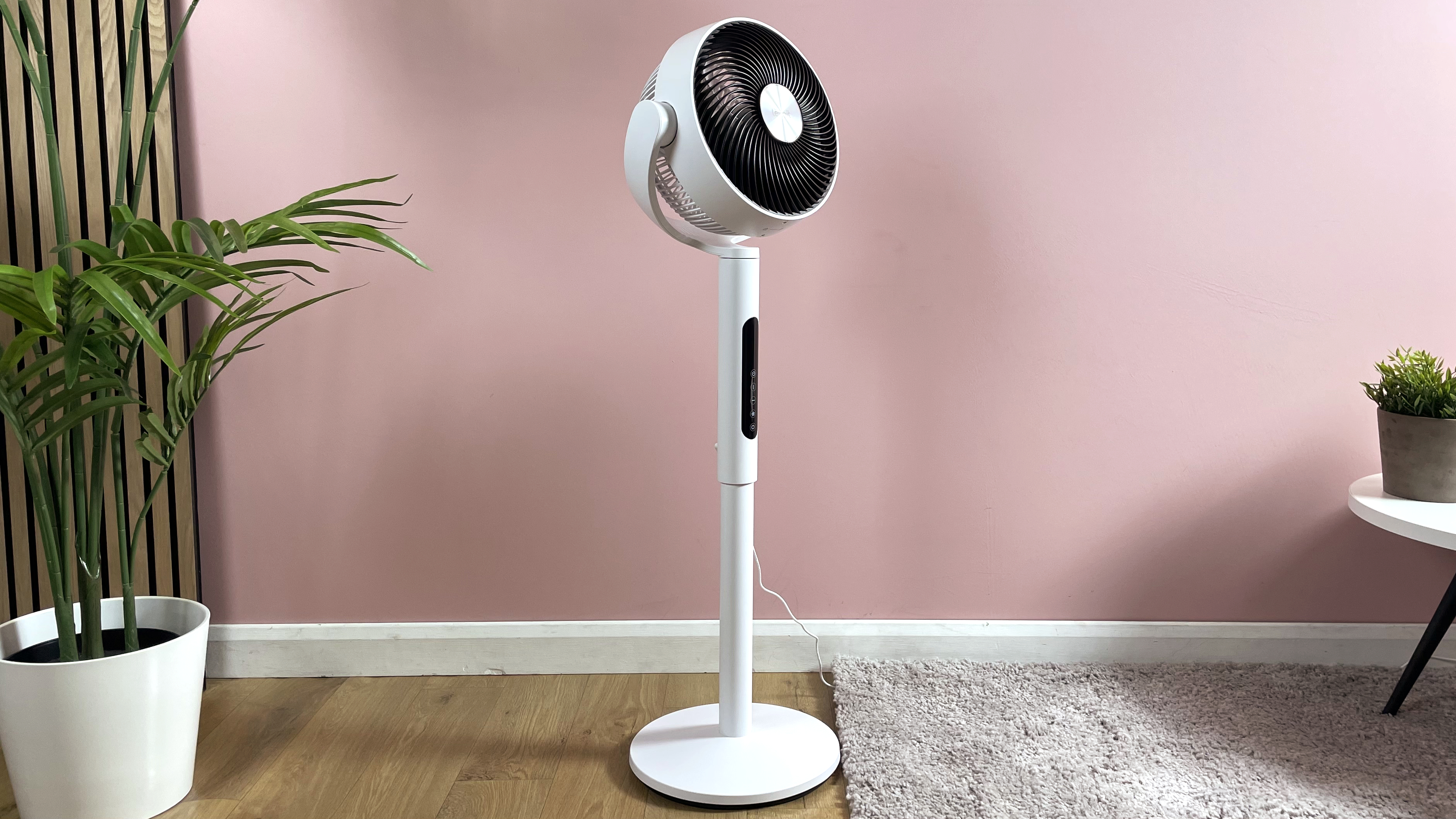 The Levoit Pedestal Air Circulator is pictured in the middle of a pink living room.