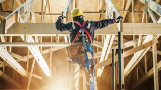 Skeleton House Frame Construction Worker Wearing Safety Harness Staying in Front on the Building and Preparing Himself For the Job.