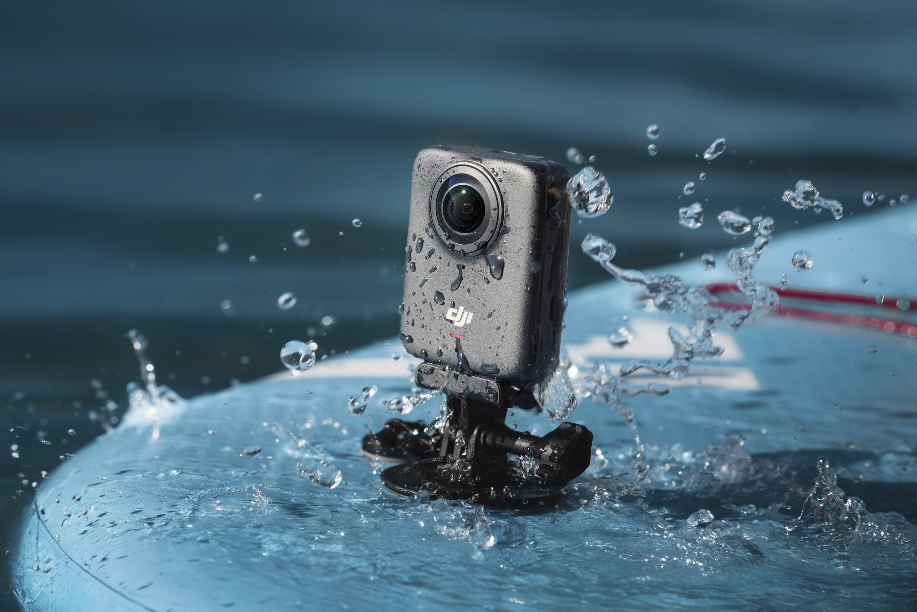 DJI Osmo 360 camera mounted to a paddle board, on the water, surrounded by water droplets
