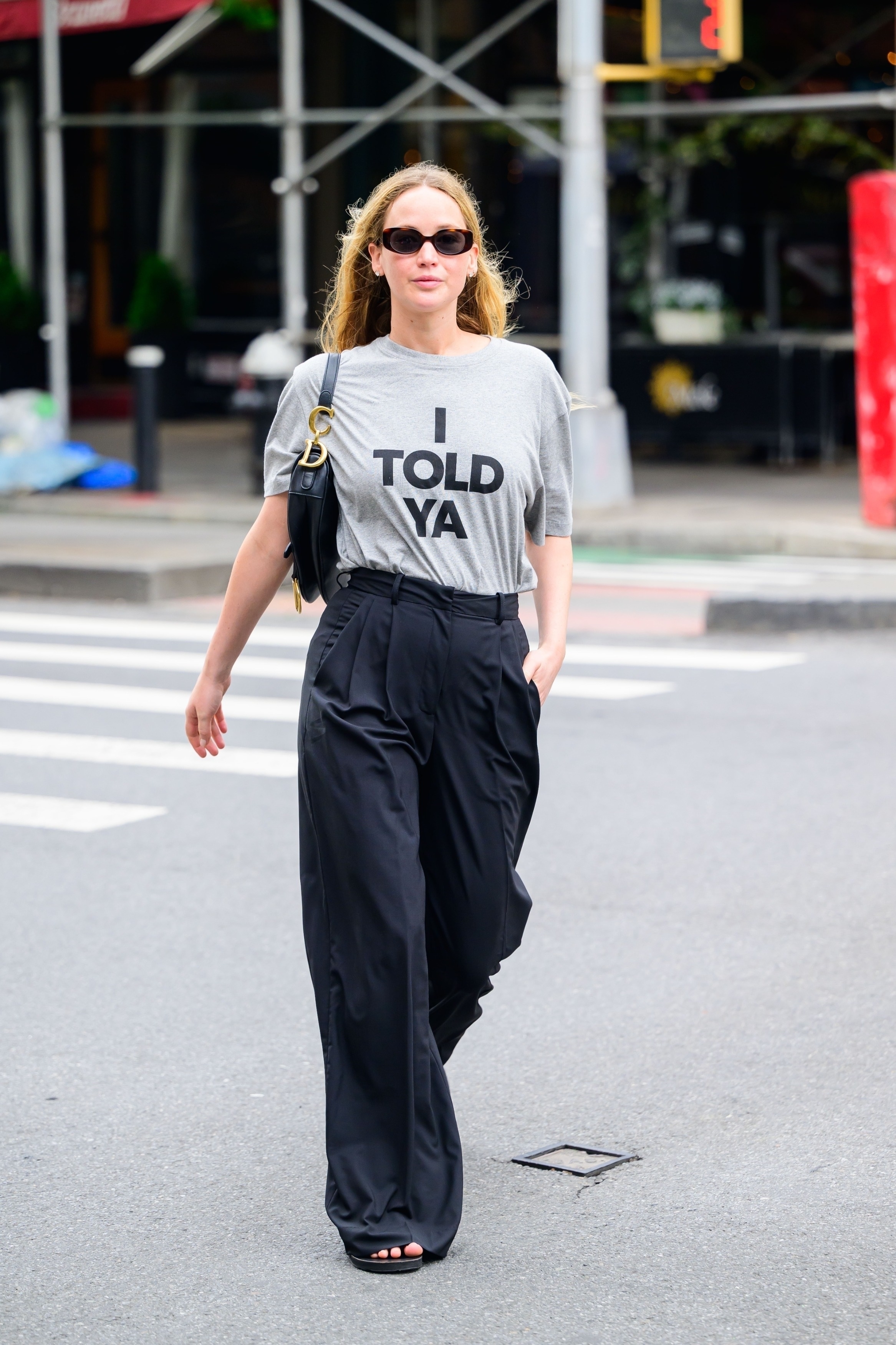 An image of Jennifer Lawrence wearing a graphic t-shirt, black wool pants and black sandals while out in New York.