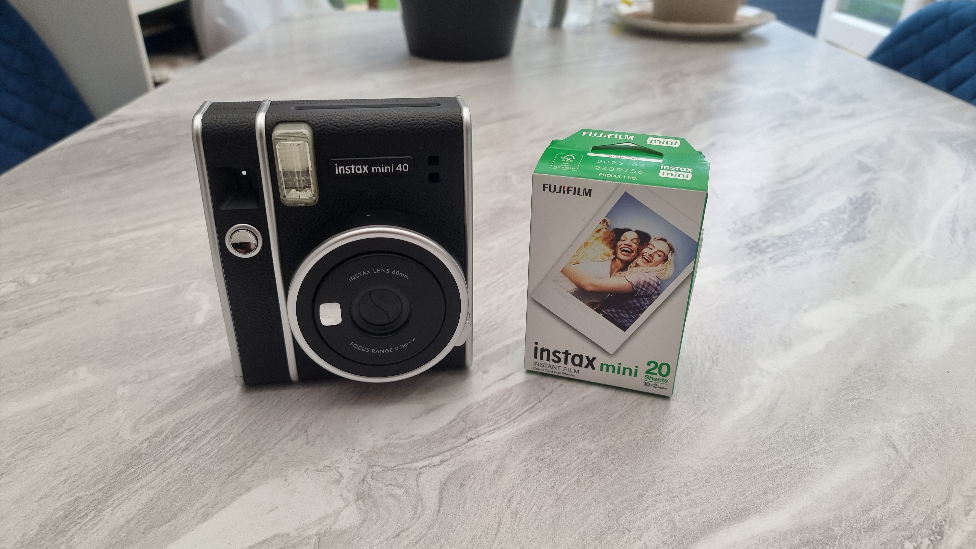 A Fujifilm Instax Mini 40 camera and film pack on a marble table