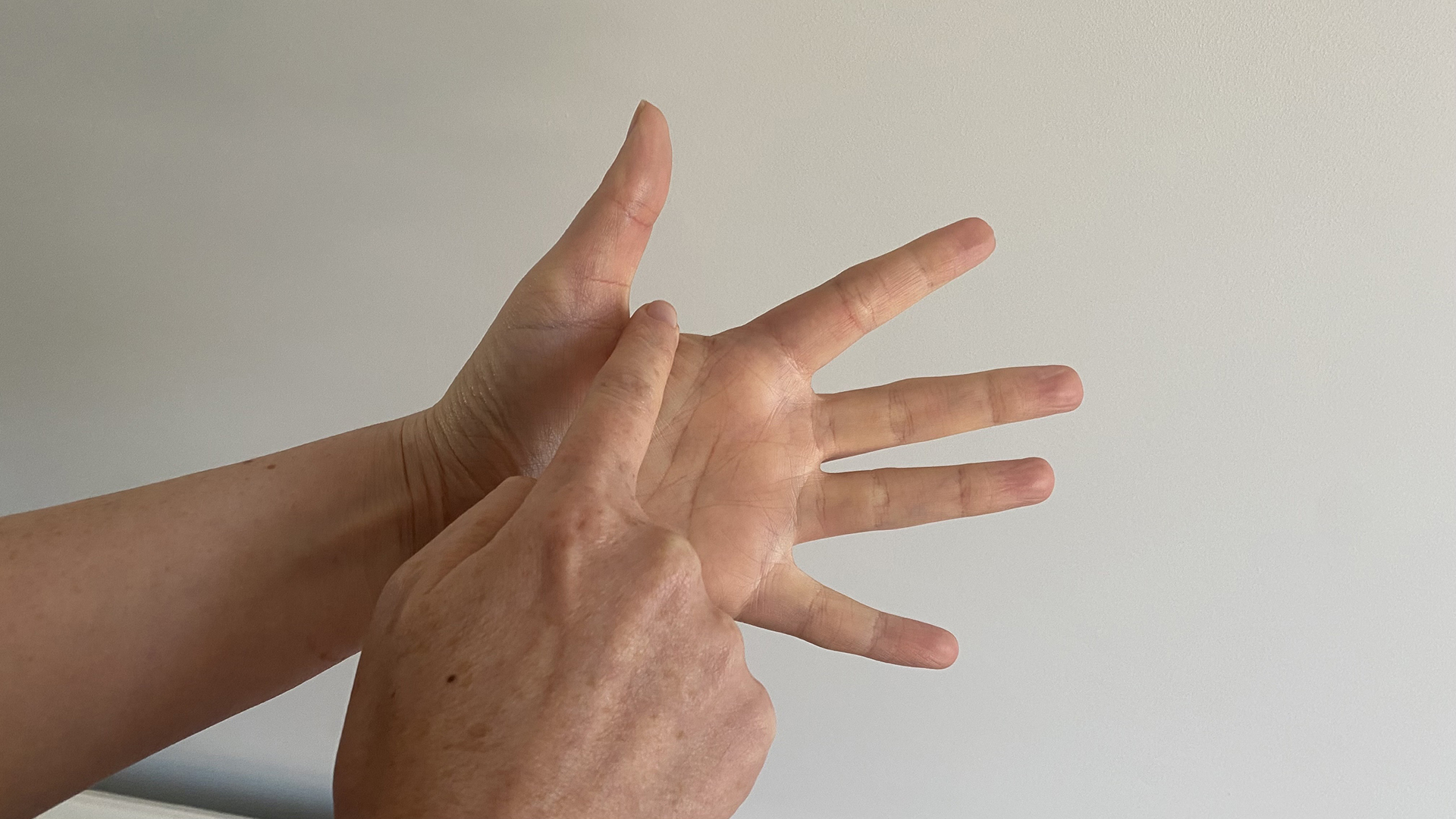 A close up of two hands using the finger breathing relaxation for technique, with the trace finger resting at the base of the thumb before tracing the index finger