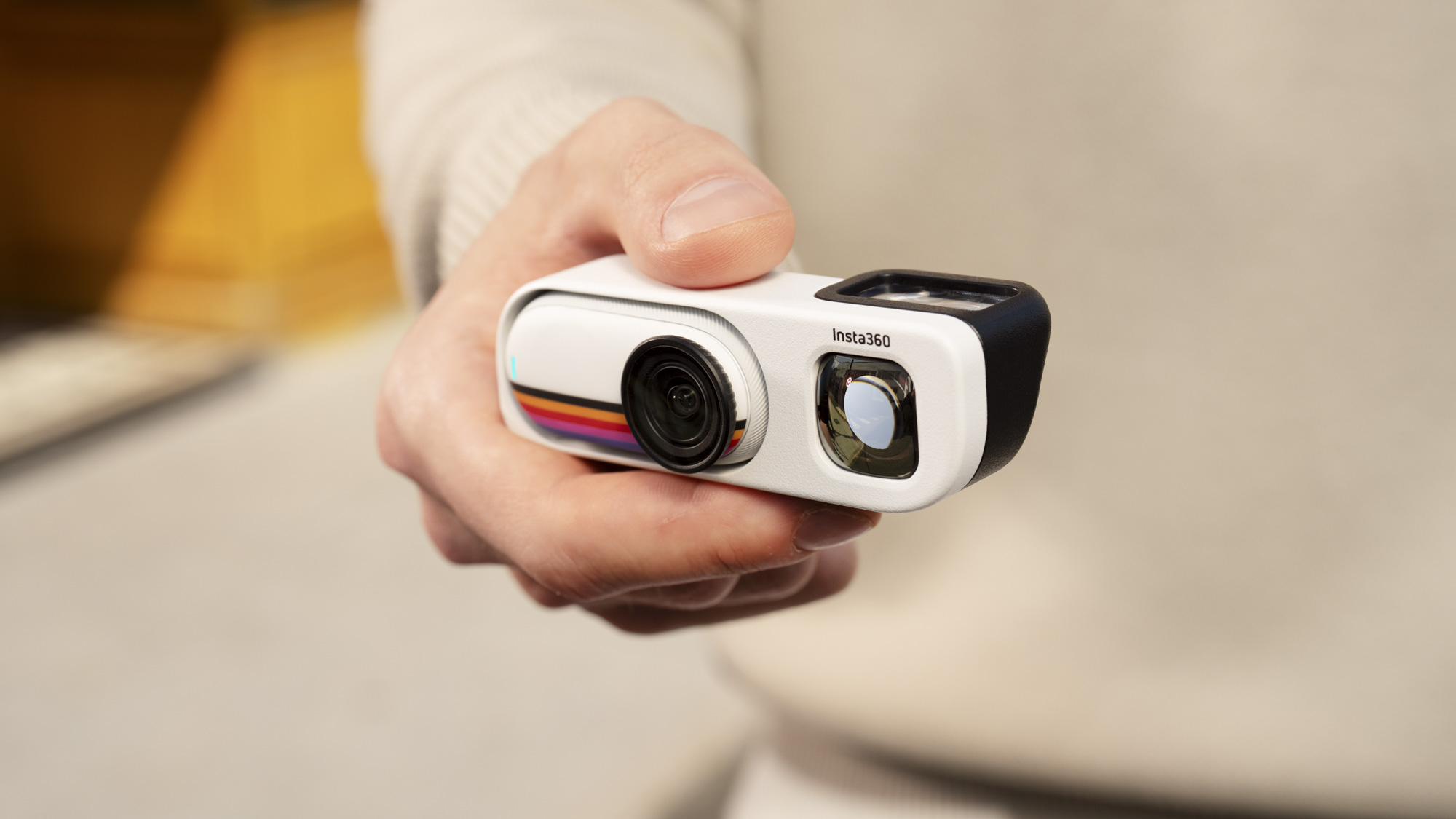 Insta360 Go 3S Retro edition, with the thumb-szied action camera slotted into the Retro Bundle's viewfinder case, held by a user