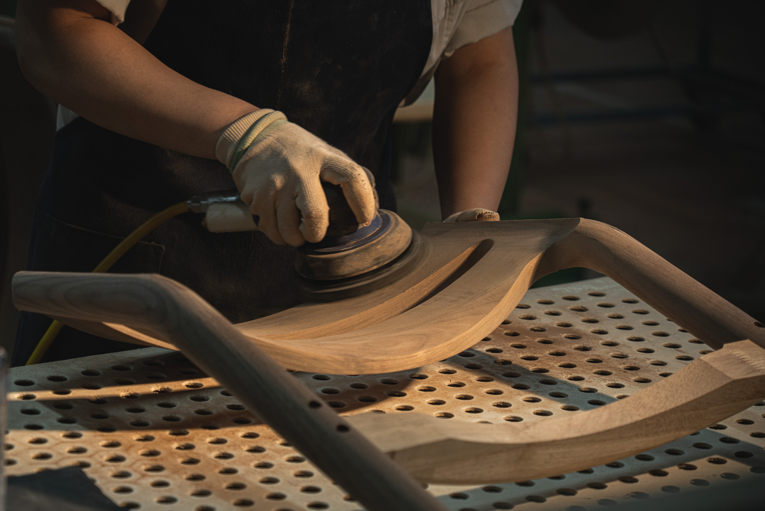 person sanding a wooden chair back at MAS