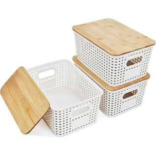 Six small white perforated storage baskets with light bamboo lids stacked in towers of three