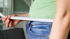 A stock photo of a person measuring their waist. 