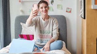 Student takes selfie on bed with Samsung Galaxy Book in front of her