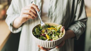 A person holding a bowl of salad