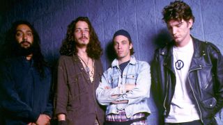 Soundgarden posing for a photograph in front of a backstage wall in 1992