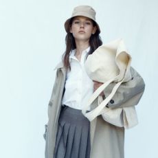 Woman wearing a tan trench coat, bucket hat, and carrying a beige bag from H&M