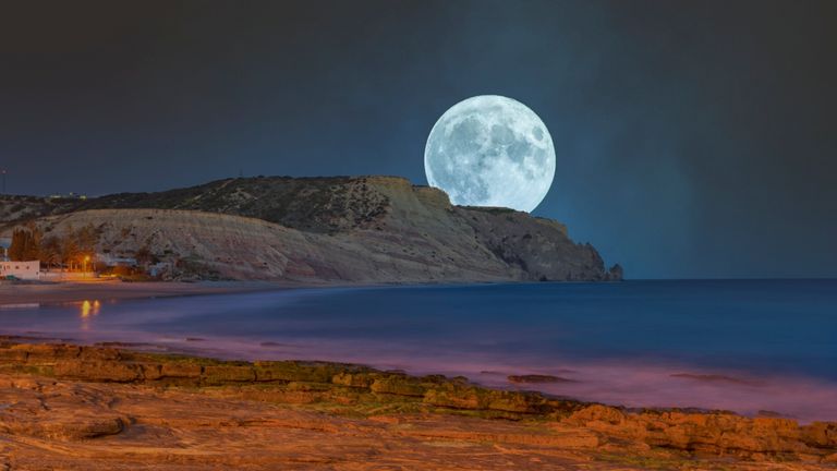 January Full Moon 2022: Full moon over the coast of Praia da Luz in the Algarve - stock photo