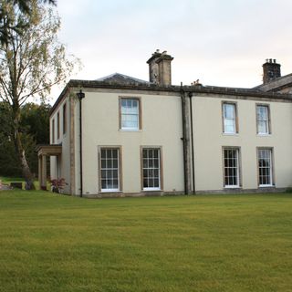 cream wall house with white frame windows and green lawn