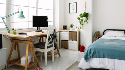 Neutral painted bedroom with bed with colourful bedding, bedside table