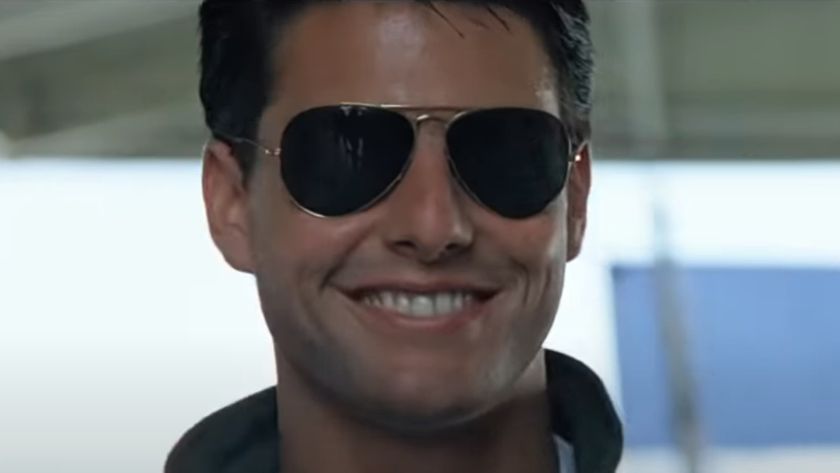 Tom Cruise grins as he wears his aviators in the hangar in Top Gun.