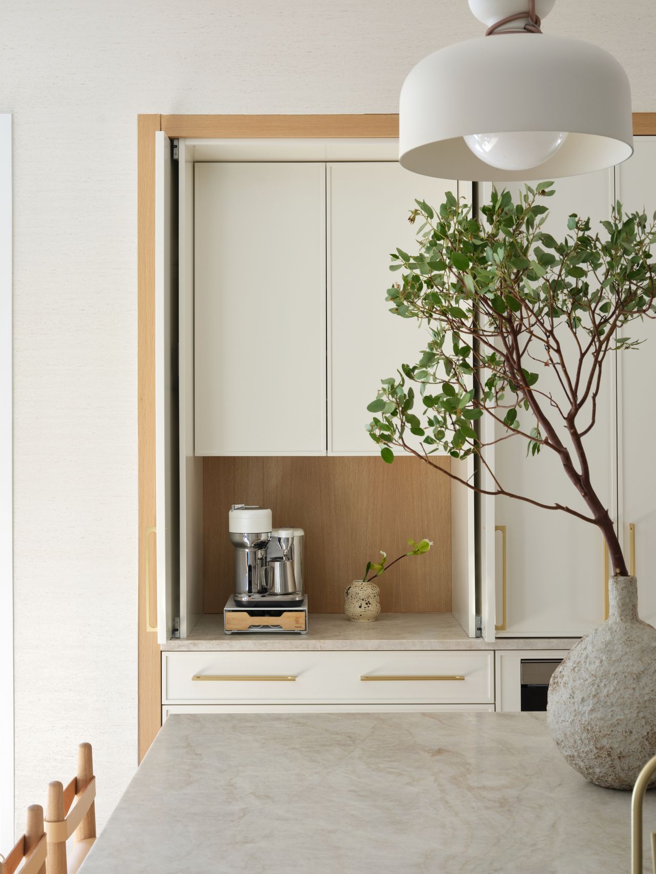 kitchen with light wood tones, white decor details, and greenery