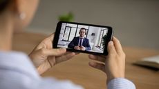 A woman consults a financial advisor via video chat on her phone.