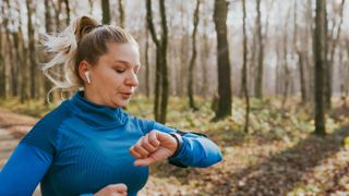 Female runner checking smartwatch while running 