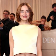 Emma Stone wearing a bob haircut to the golden globes. She is also wearing a yellow sleeveless top. 