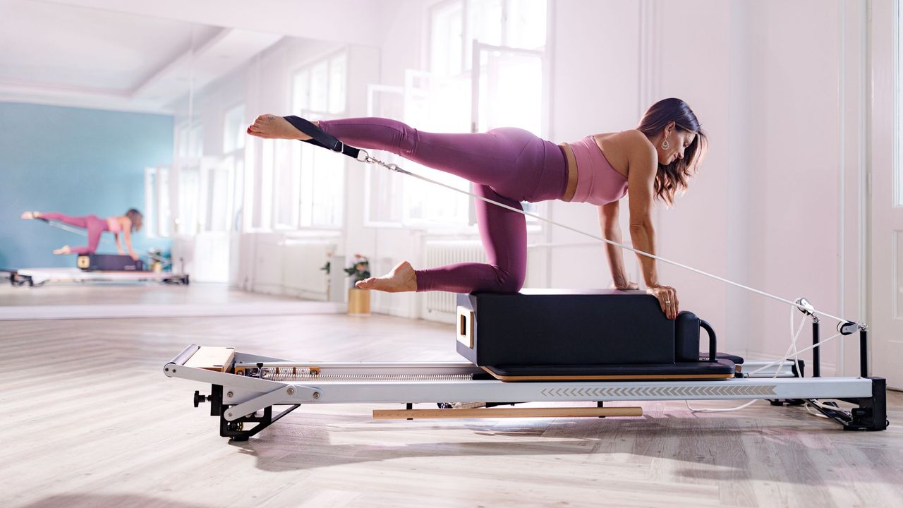 A woman doing one of the best intermediate Pilates exercises on a Reformer machine