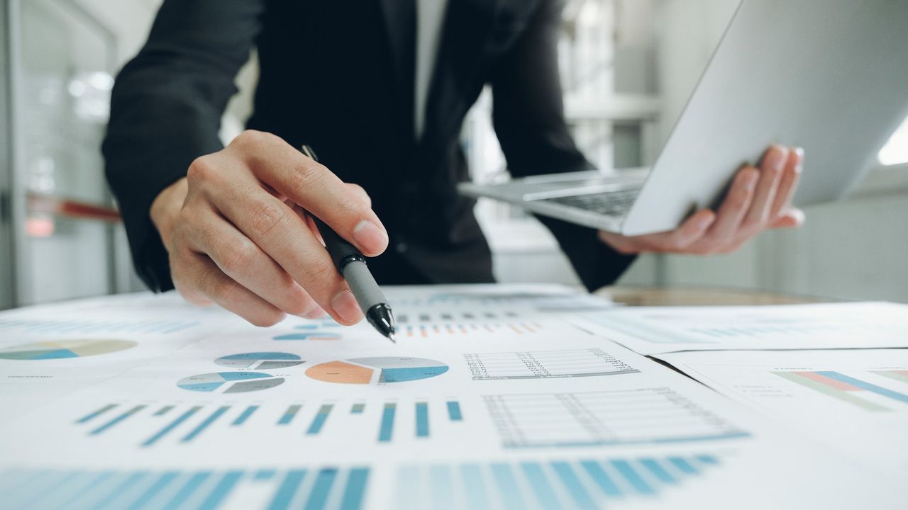 An investing professional looks at a desk covered in pie charts and bar graphs.