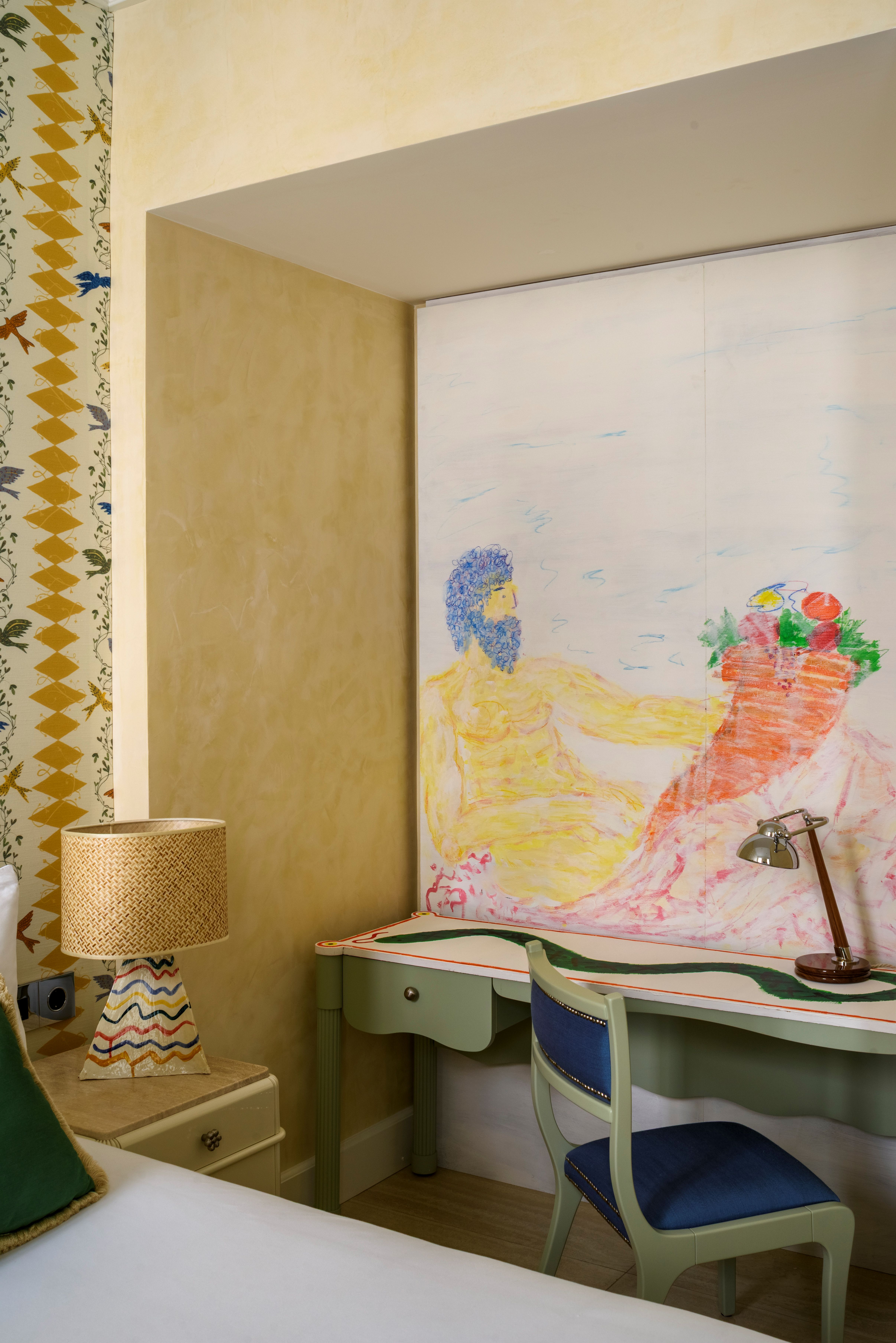 A hotel room with hand-drawn sketches, patterned curtains and furniture, and sleek wooden cabinets and accent lights styled into a maximalist-chic scheme with an ochre-led palette.