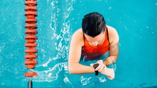 Woman checks her swimming watch in the pool