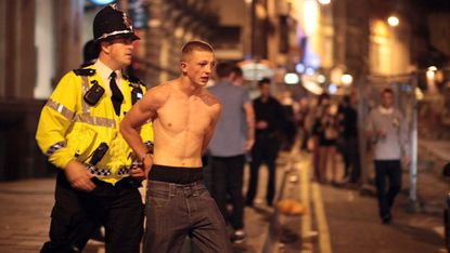 A drunken man is led away by Police officers 