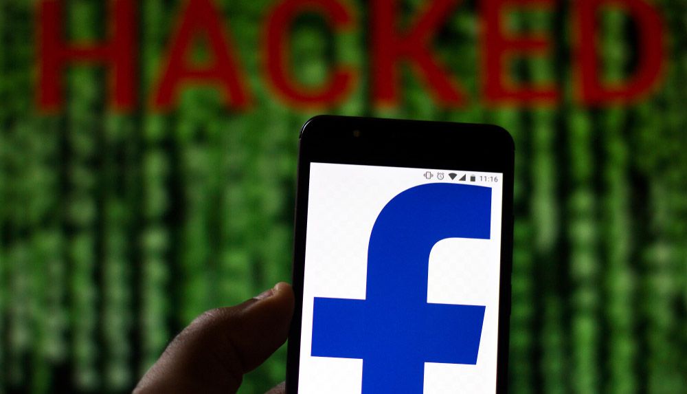 Facebook logo on Android phone superimposed over word &#039;HACKED&#039; on Matrix-like screen.