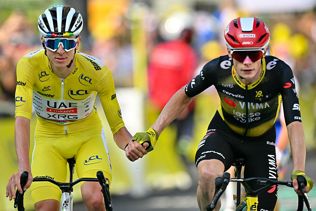 TOPSHOT - UAE Team Emirates - XRG team's Slovenian rider Tadej Pogacar wearing the overall leader's yellow jersey (L) and Team Visma - Lease a bike team's Danish rider Jonas Vingegaard (R) cross the finish line hand in hand after the 10th stage of the 112th edition of the Tour de France cycling race, 165.3 km between Ennezat and Le Mont-Dore Puy de Sancy, in central France, on July 14, 2025. (Photo by Loic VENANCE / AFP) (Photo by LOIC VENANCE/AFP via Getty Images)