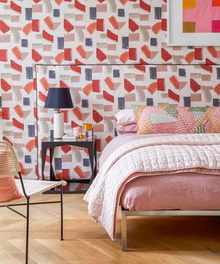 Bright, abstract wallpaper ideas for bedrooms illustrated in blue, pink and gray with matching headboard and a pink and white dressed bed.