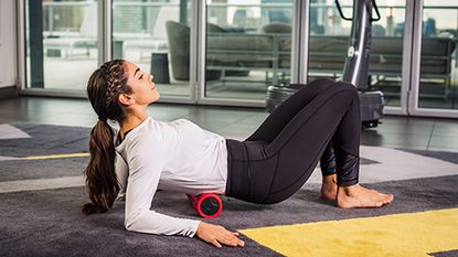person using Power Plate roller on their lower back 